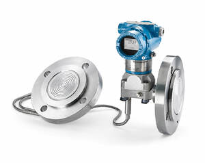 Industrial pressure transmitter with blue digital display connected to stainless steel flanges on a white background.