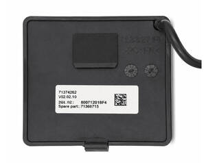 Back of a black electronic device with a white label, two small screws, a raised square section, and a cable entering from the right side.