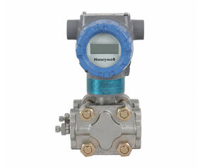 Honeywell flow transmitter with a blue circular display mounted on a silver valve body with brass bolts.