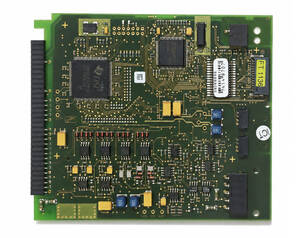 Green printed circuit board (PCB) densely populated with ICs, capacitors, and resistors; edge connector on the left and various mounted components.